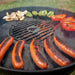 Arteflame Weber-style replacement grate, grilling sausages and peppers, highlighting the grill's even heat distribution.