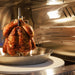 A succulent chicken roasting on the rotisserie inside the Blaze Grills 26-Inch Gas Outdoor Pizza Oven.
