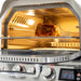 Interior view of the Blaze Grills 26-Inch Gas Outdoor Pizza Oven with a chicken on the rotisserie and the temperature display in the foreground