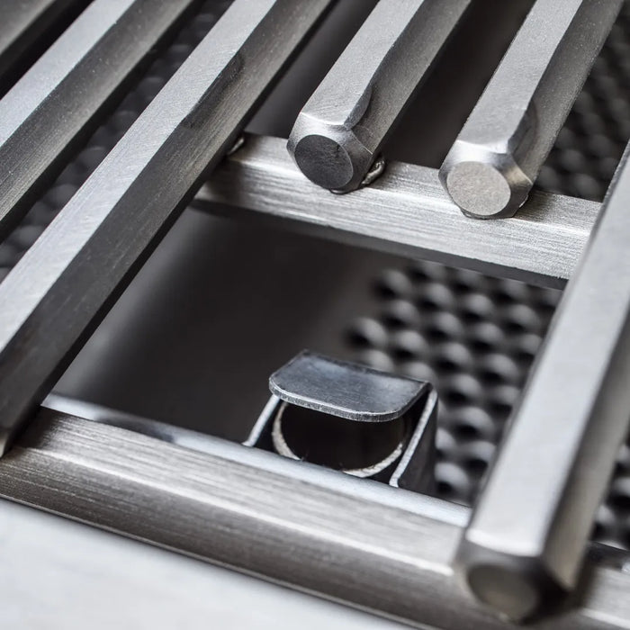 Close-up of the cooking grates on a gas grill, with a focus on the round rod design and the ignition rail beneath.