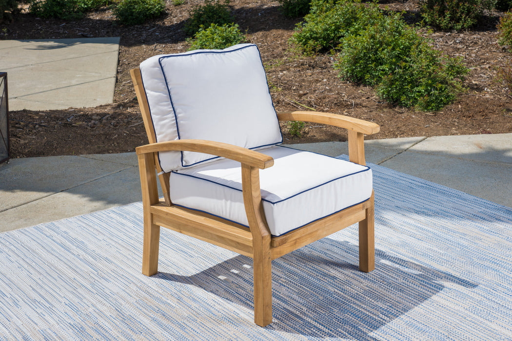 A Tortuga Outdoor 6-Piece Indonesian Teak Sofa and Fire Table Set - Canvas Natural or Navy luxury retreat patio chair with a white cushion on a blue rug.