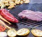 Arteflame grill grate with a steak and vegetables, emphasizing the professional sear achieved on the steel surface.