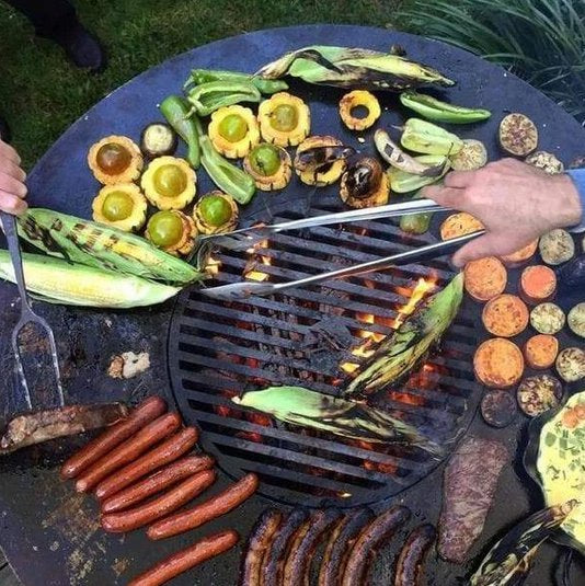 An immersive grilling experience on the Arteflame Classic 40" Grill with a variety of vegetables and sausages.