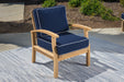 A durable Tortuga Outdoor teak chair with a blue cushion on a rug.