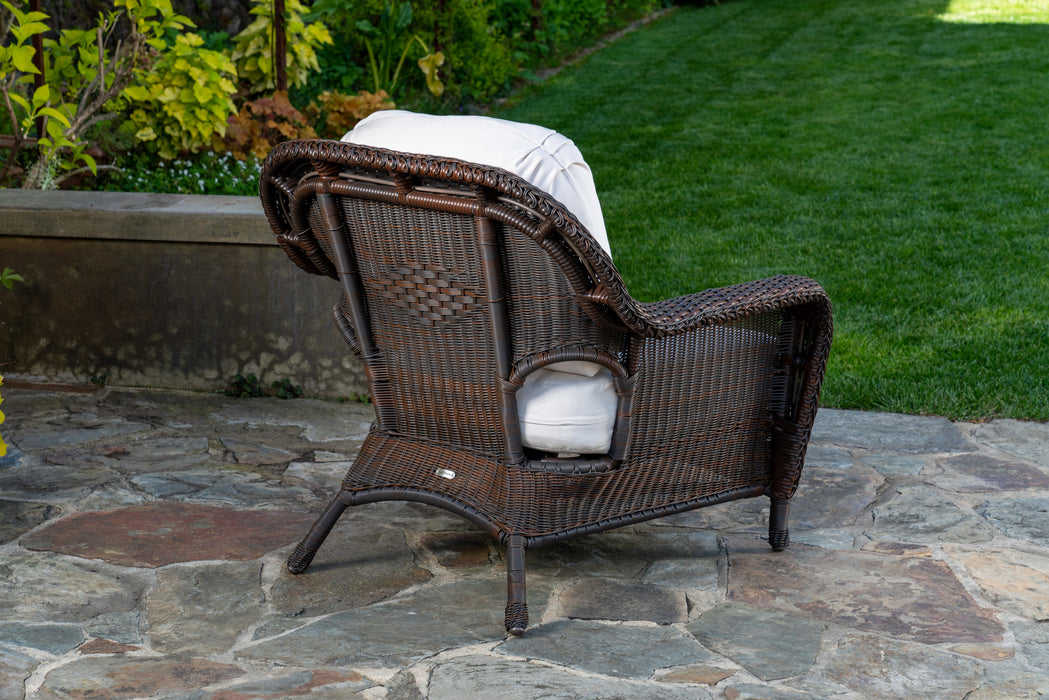 Rear view of the club chair from the Tortuga Outdoor Sea Pines 5-Piece Outdoor Wicker Conversation Set - Java sitting on a stone patio.