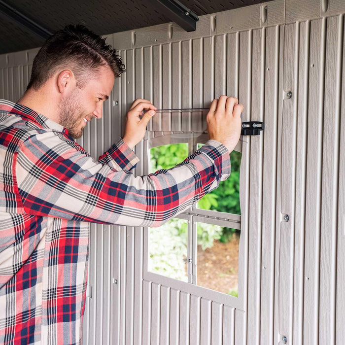 A man is opening a window in a Lifetime 8 Ft. X 12.5 Ft. Outdoor Storage Shed - 6402 shed.