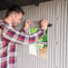 A man is opening a window in a Lifetime 8 Ft. X 12.5 Ft. Outdoor Storage Shed - 6402 shed.