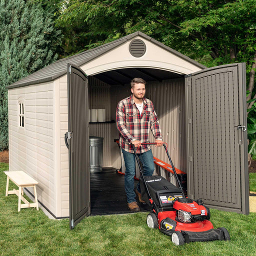 A man is standing in front of a Lifetime 8 Ft. X 12.5 Ft. Outdoor Storage Shed - 6402.