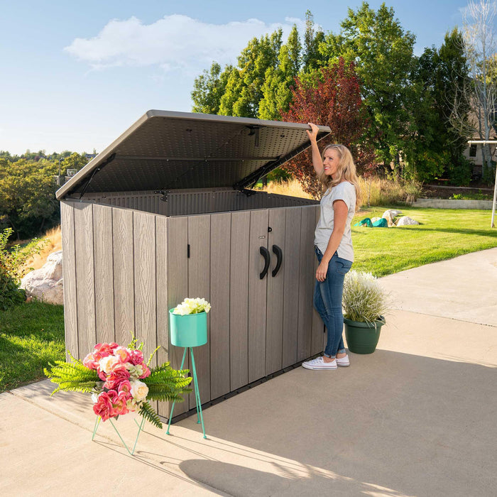A woman standing next to a Lifetime Horizontal Storage Shed (75 Cubic Feet) - 60341.