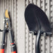 A pair of Lifetime Utility Shed - 60331U shovels and a rake hanging on a wall.