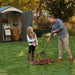 A man and a girl raking leaves in front storage with doors opened 