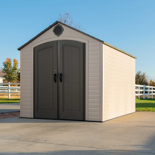 An angled view of a shed on a concrete driveway.