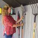 A woman holding a Lifetime 10 Ft. X 8 Ft. Outdoor Storage Shed - 60243 in a storage shed.