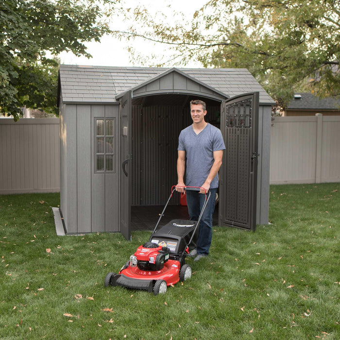 A man with a Lifetime 10 Ft. X 8 Ft. Outdoor Storage Shed - 60330 in front of a shed.