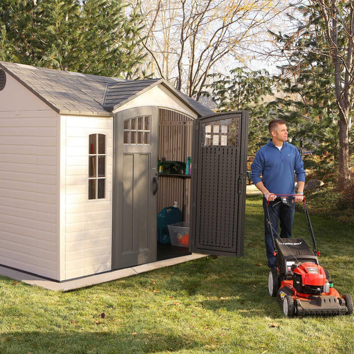 A man is standing in front of a Lifetime 10 Ft. X 8 Ft. Outdoor Storage Shed - 60333.