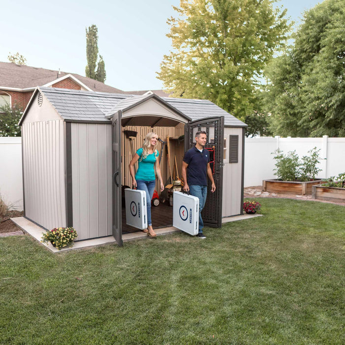 Two people standing in front of a Lifetime 12.5 Ft. X 8 Ft. Outdoor Storage Shed - 60223.