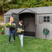 A woman and a child standing in front of a Lifetime 15 Ft X 8 Ft Outdoor Storage Shed - 60318.