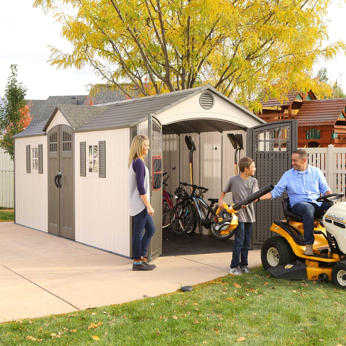 Three people interacting with equipment by the side doors of a shed