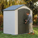 A man opening the door of an Outdoor Storage Shed placed in a yard