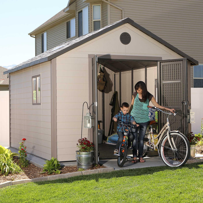 A woman and a child in front of a Lifetime 11 Ft. X 13.5 Ft. Outdoor Storage Shed - 6415.