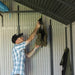 A man is hanging a Lifetime 11 Ft. X 13.5 Ft. Outdoor Storage Shed - 6415 in a metal shed.
