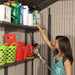 A woman holding a Lifetime 11 Ft. X 13.5 Ft. Outdoor Storage Shed - 6415 in a storage shed.