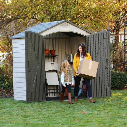 A woman and a child interacting outside of a Storage Shed on the lawn