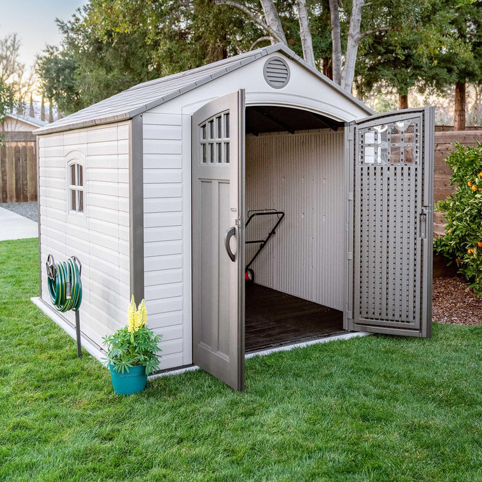 A storage shed in a backyard with a door open.
