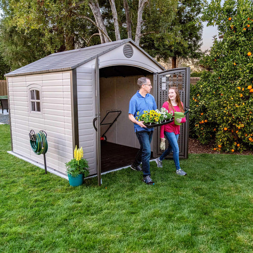 Two people interacting by the equipment shed with two doors open 