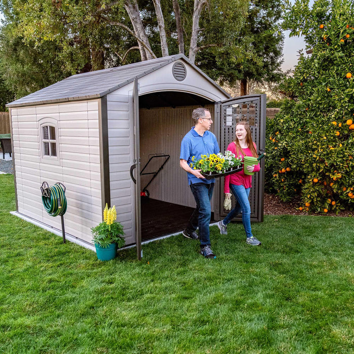 Two people interacting by the equipment shed with two doors open 
