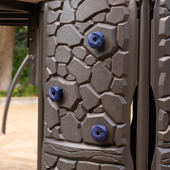 Close-up of the climbing wall section of the Lifetime Adventure Castle, showcasing the texture and blue climbing grips.
