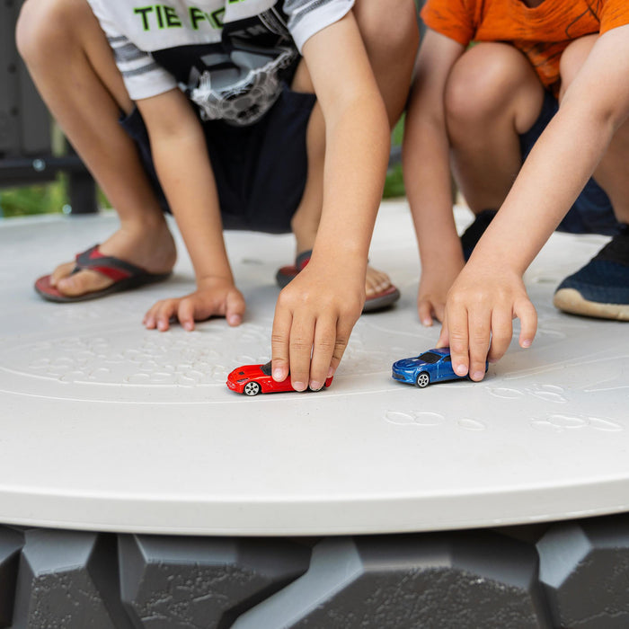 Children's hands playing with toy cars on the white table of the Lifetime Adventure Castle playset.