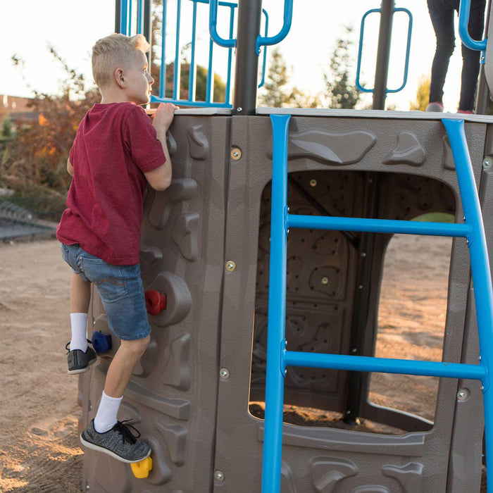 A young boy climbs the rock wall of the Lifetime Adventure Tower playset, with focus on his hands gripping the colorful climbing stones.