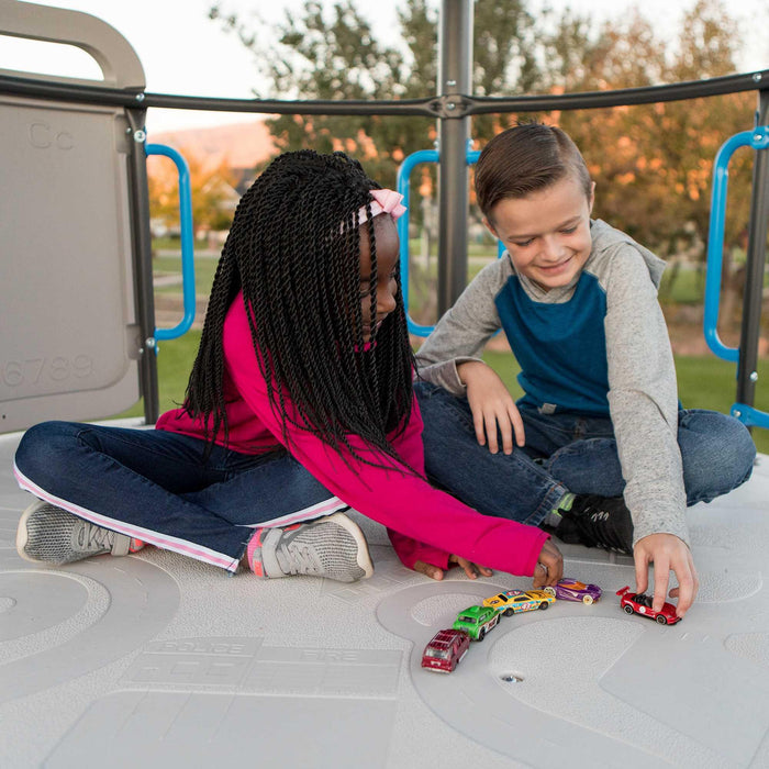 Two children seated on the grey platform of the Lifetime Adventure Tower playset, playing with colorful toy cars.