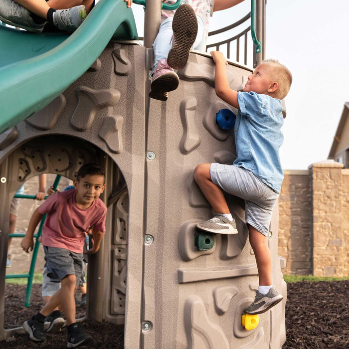 A boy climbing the wall of the Lifetime Double Adventure Tower.