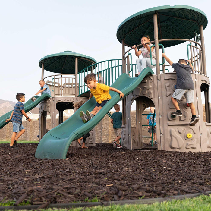 Kids playing on the Lifetime Double Adventure Tower with a young boy sliding down the green slide.
