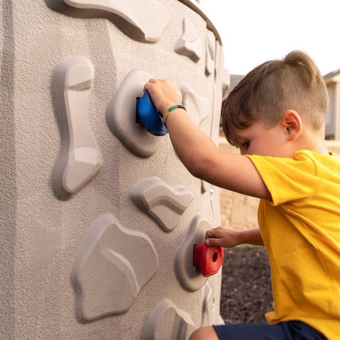 A boy wearing a yellow shirt climbing the walls of Lifetime Double Adventure Tower.