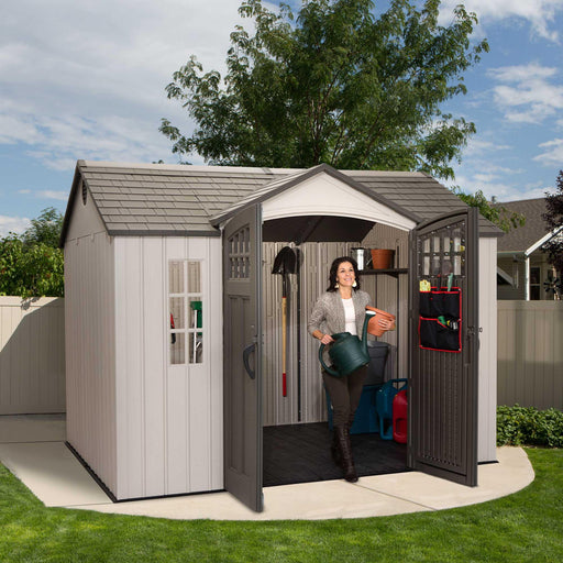 A woman is standing in front of a Lifetime 10 Ft. X 8 Ft. Outdoor Storage Shed - 60118.