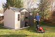 A man standing in front of a Lifetime 10 Ft. X 8 Ft. Outdoor Storage Shed - 60178.