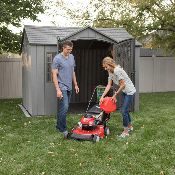 A man and woman standing in front of a Lifetime 10 Ft. X 8 Ft. Outdoor Storage Shed - 60330.