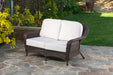 A Tortuga Outdoor Sea Pines Java Loveseat is set on a stone patio, showcasing all-weather resilience.