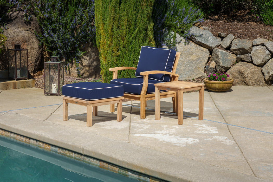 A Tortuga Outdoor 3-Piece Indonesian Teak Club Chair Set - Canvas Natural or Navy, including a chair and ottoman, featuring all-weather resin wicker, perfect for lounging by a pool.