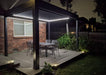 An Aluminum pergola with table and chairs at night.
