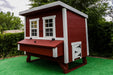 A vibrant red OverEZ Jumbo Chicken Coop with white trim and multiple windows, offering a spacious and comfortable home for poultry.