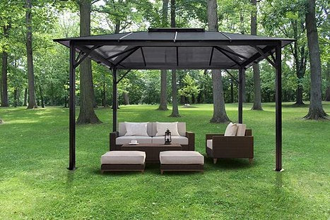 Paragon Outdoor Madrid Hard Top Gazebo situated in a park-like setting, featuring comfortable modern outdoor furniture on grass.