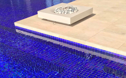 A luxurious Solus Decor Halo Low 60K BTU Fire Pit positioned by the pool with a blue mosaic tile, enhancing the tranquil and opulent poolside atmosphere.