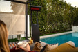 Cozy poolside evening with a Bromic Tungsten 500 Series portable heater providing warmth to a relaxing outdoor seating area.