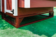 Close-up of the protective mesh base feature of a red OverEZ small chicken coop, part of the Small Flock Bundle Pro, on artificial green grass.