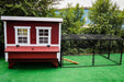 Frontal view of an OverEZ Regular 8-foot Chicken Run attached to a large, red and white chicken coop with dual windows and access ramp.