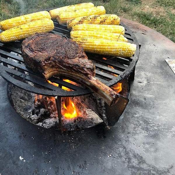 Stainless steel Arteflame riser enhancing the grilling experience with elevated cooking space for a steak and corn.